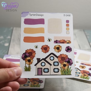 May include: A sheet of stickers featuring a house with a purple door, two bee stickers, and multiple flower stickers in shades of orange, brown, and purple. The sheet also includes a color palette and the text "TyrianDesign" and "ST-10498".