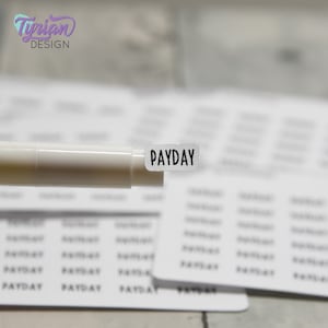 May include: A white sticker with the word "PAYDAY" printed in black. The sticker is being held by a white marker.