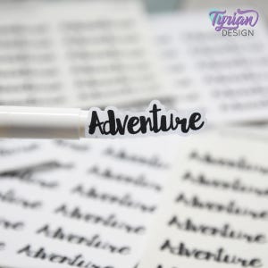 May include: A clear sticker with the word "Adventure" in black script is affixed to a white pen. The background is filled with similar stickers, creating a pattern. The upper right corner features a logo with the text "Tyrian Design".