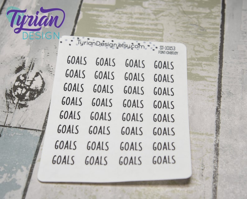 May include: A sheet of white stickers with the word "GOALS" printed in a black, sans-serif font. The stickers are arranged in rows and columns. The text "Tyrian Design" is in the upper left corner. The text "TyrianDesign.etsy.com" is at the top.