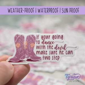Może przedstawiać: Biała naklejka z napisem "If your going to dance with the devil make sure he can two step." Naklejka przedstawia parę fioletowych butów kowbojskich z pomarańczowymi kwiatowymi akcentami. Naklejka jest odporna na warunki atmosferyczne, wodoodporna i odporna na słońce.