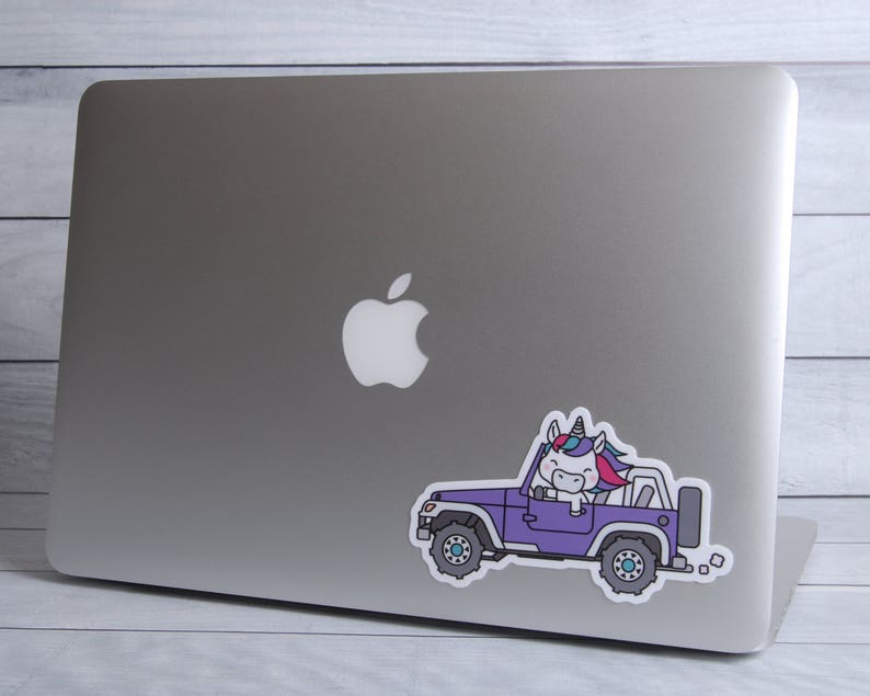 Puede incluir: Una pegatina de un jeep morado con un unicornio conduciendo. El unicornio tiene una crin y una cola azul, rosa y blanca. El jeep tiene ruedas negras y un fondo blanco.