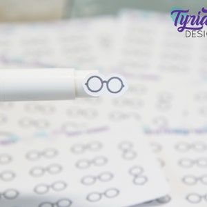 May include: A white marker pen with a small black and white sticker of a pair of glasses on the end.