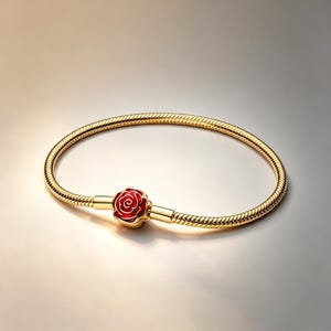 Op de afbeelding: Een goudkleurige slangenkettingarmband met een centrale bedel in de vorm van een bloeiende roos. De roosbedel is gedetailleerd met felrood emaille in de bloemblaadjes, wat contrasteert met het gepolijste goudkleurige metaal van de armband.