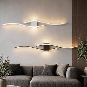May include: Two horizontal wall-mounted light fixtures, one white and one black, each featuring a central rectangular base and two curved, wave-like arms extending outward that emit a warm, soft glow from integrated LED strips.