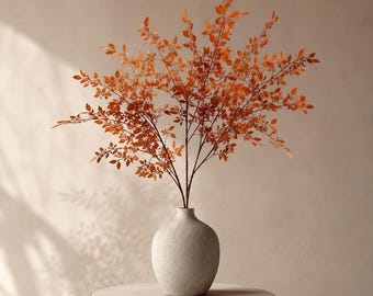 Peut inclure: Un arrangement décoratif de tiges fines et ramifiées portant de petites feuilles orange vif. Les tiges sont placées dans un vase rond beige clair à la finition mate et texturée, formant un ensemble botanique équilibré et symétrique.