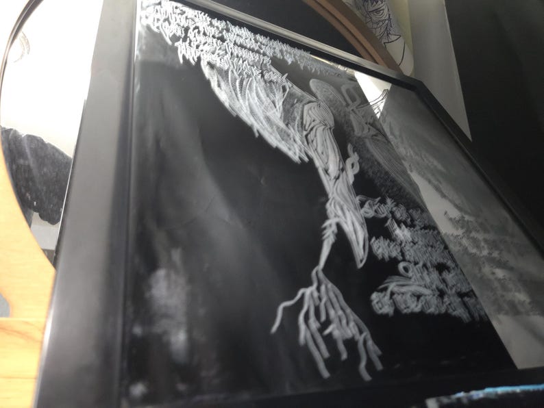 May include: A black framed wall art piece featuring a high-contrast white graphic illustration on a black background. The artwork depicts a stylized, elongated figure with branch-like appendages and intricate, flowing white line work throughout.