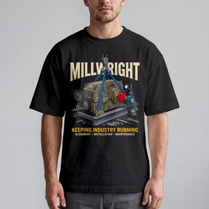 May include: A black t-shirt featuring a graphic of a tan industrial gearbox being lifted by blue straps. The text reads MILLWRIGHT, KEEPING INDUSTRY RUNNING, ALIGNMENT, INSTALLATION, MAINTENANCE. Tools are scattered on the base below the machinery.