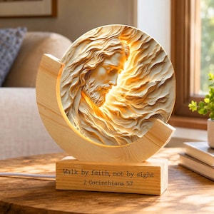 May include: A circular light fixture featuring a relief carving of a face with flowing hair and beard. The piece is mounted on a rectangular wooden base with the text "Walk by faith, not by sight 2 Corinthians 5:7" engraved on the front.