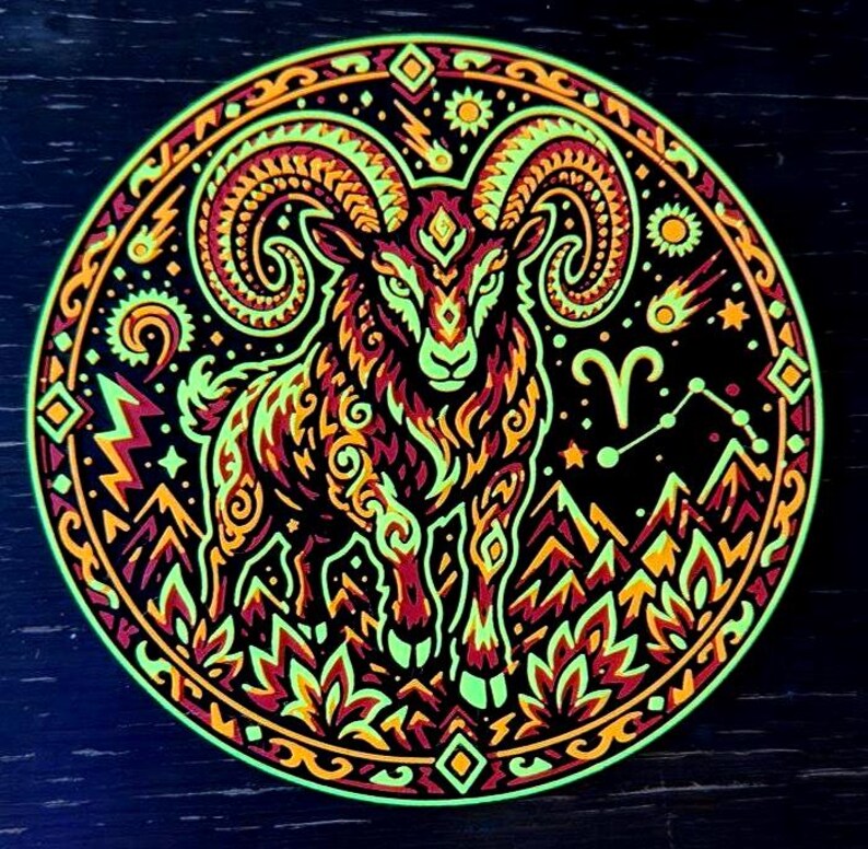 Puede incluir: Una pegatina circular con un carnero estilizado de grandes cuernos curvados, en tonos verde ne&oacute;n, naranja y rojo sobre fondo negro. El dise&ntilde;o incluye elementos celestiales como estrellas, un cometa y el s&iacute;mbolo del zodiaco Aries.