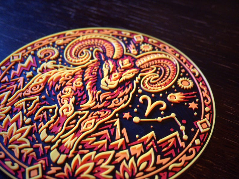Puede incluir: Un posavasos circular con un dise&ntilde;o en relieve de varias capas que muestra un carnero con grandes cuernos curvados. La ilustraci&oacute;n utiliza una paleta de colores vibrantes en amarillo, naranja y rojo sobre un fondo oscuro con estrellas.