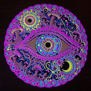 May include: A circular layered wall art piece featuring a central eye design surrounded by mushrooms, a crescent moon, and intricate geometric patterns in vibrant neon pink, electric blue, lime green, and deep brown on a black background.