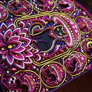 Pu&ograve; includere: Un'opera d'arte in legno tagliata al laser a pi&ugrave; strati con motivi intricati in tonalit&agrave; vivaci di magenta, viola, giallo e nero. Il design include gatti stilizzati, funghi e un grande fiore di loto, il tutto disposto in una composizione complessa e simmetrica con un profondo rilievo dimensionale.