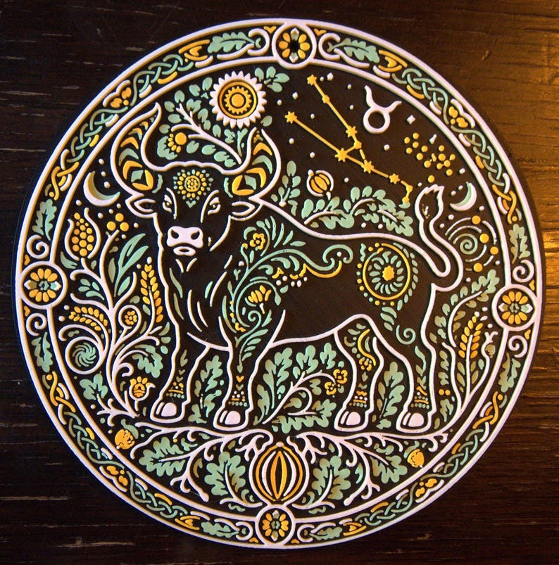 Może przedstawiać: Okrągła ozdobna tabliczka z ilustracją czarnego byka ozdobioną misternymi jasnozielonymi i ż&oacute;łtymi wzorami kwiatowymi. Projekt zawiera symbol zodiaku Byka, gwiazdozbi&oacute;r oraz szczeg&oacute;łową obw&oacute;dkę z węzłami w stylu celtyckim.
