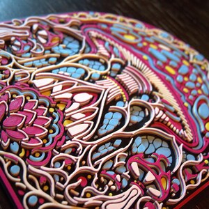 May include: A multi-layered, three-dimensional wall art piece featuring an intricate mushroom design. The artwork is composed of stacked, laser-cut layers in vibrant shades of magenta, light blue, yellow, and cream, creating a textured relief.