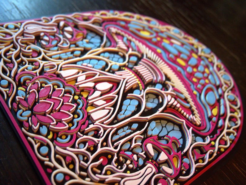 May include: A multi-layered, three-dimensional wall art piece featuring an intricate mushroom design. The artwork is composed of stacked, laser-cut layers in vibrant shades of magenta, light blue, yellow, and cream, creating a textured relief.