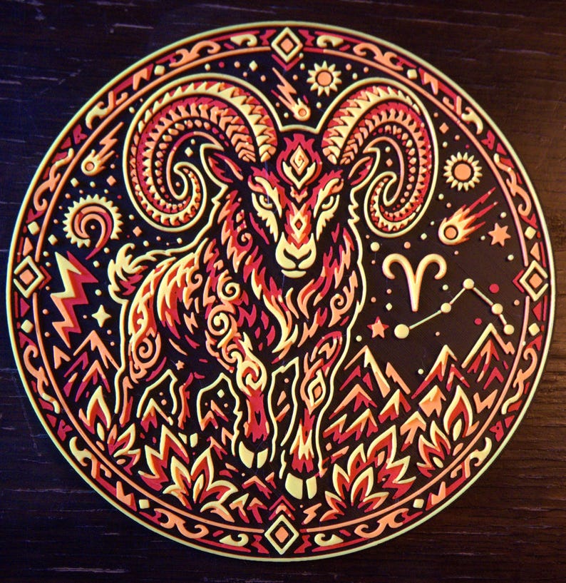 Puede incluir: Una pegatina circular con un carnero estilizado en tonos rojos, naranjas y amarillos sobre un fondo negro. El dise&ntilde;o incluye patrones intrincados, monta&ntilde;as, llamas, estrellas, un cometa y el s&iacute;mbolo del zodiaco Aries con su constelaci&oacute;n.