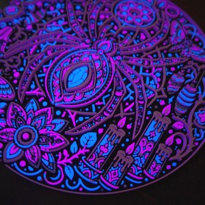 Close relief view of Arachnomancer under active UV blacklight, showing radial web and gothic details.