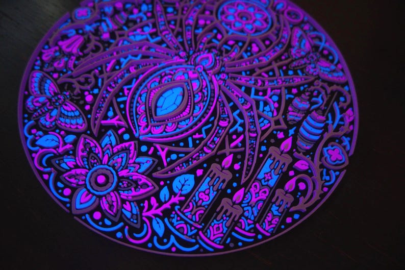 Close relief view of Arachnomancer under active UV blacklight, showing radial web and gothic details.
