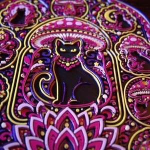 Pu&ograve; includere: Un'opera d'arte da parete multistrato con una silhouette centrale di gatto nero circondata da intricati motivi di funghi, lune crescenti e disegni floreali in vivaci tonalit&agrave; di magenta, viola, giallo e bianco su uno sfondo scuro.