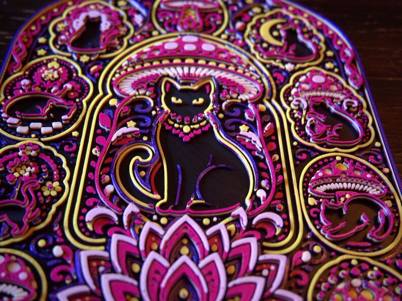 Pu&ograve; includere: Un'opera d'arte da parete multistrato con una silhouette centrale di gatto nero circondata da intricati motivi di funghi, lune crescenti e disegni floreali in vivaci tonalit&agrave; di magenta, viola, giallo e bianco su uno sfondo scuro.