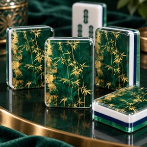 K&ouml;nnte beinhalten: Vier rechteckige Mahjong-Spielsteine mit einem tief smaragdgr&uuml;nen, marmorierten Hintergrund und goldenen Bambusblatt-Illustrationen. Die Steine haben eine klare Acryloberfl&auml;che, eine wei&szlig;e Basis und einen d&uuml;nnen dunkelblauen Streifen zwischen den Bereichen.