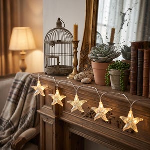 May include: A string of five illuminated starfish-shaped lights with a textured, translucent finish. Each starfish contains a warm-toned light bulb, connected by a thin, flexible wire, creating a glowing decorative accent for interior spaces.