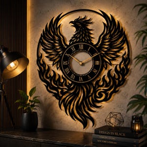 Könnte beinhalten: Eine runde Wanduhr mit einer schwarzen Phönix-Silhouette aus Metall, die ausgebreitete Flügel und Flammen zeigt. Das Zifferblatt hat goldfarbene Zeiger und römische Ziffern. Das Design ist hinterleuchtet und erzeugt einen warmen Schein.