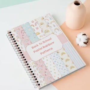 Może przedstawiać: Notatnik spiralny z okładką w pionowe paski z pastelowymi wzorami tęczy oraz centralną białą etykietą z napisem Back to School Pastel Rainbow Patterns wydrukowanym brązową czcionką bezszeryfową.