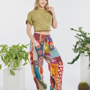 May include: Loose-fitting trousers featuring a vibrant patchwork design with various colourful fabric patterns, including red, blue, yellow, and purple sections. The trousers have an elastic waistband with a drawstring and two large front pockets.