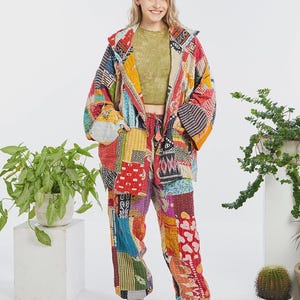 Pode incluir: Um conjunto de casaco e calças em patchwork com uma mistura vibrante de quadrados de tecido multicoloridos com diversos padrões geométricos e florais, incluindo tons de vermelho, amarelo, azul e verde, sobre um top curto verde-azeitona.