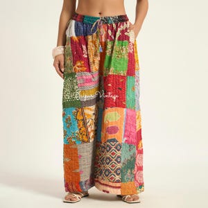 Könnte beinhalten: Weit geschnittene Hose mit Patchwork-Design aus verschiedenen bunten Blumen- und geometrischen Mustern. Der Stoff weist durchgehend sichtbare Steppnähte im Kantha-Stil auf. Die Hose hat einen elastischen Bund mit Kordelzug und den Text Jaipur Vintage.