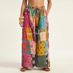 May include: Wide-leg pants featuring a patchwork design with various colorful fabric patterns including pink, yellow, blue, and green. The pants have an elastic waistband with a drawstring and visible stitching throughout. The text Jaipur Vintage is visible.