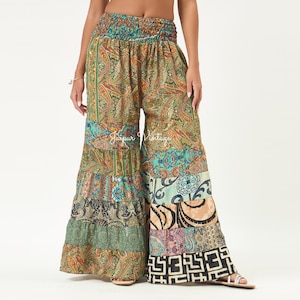 May include: Wide-leg trousers featuring a high-waisted smocked band and a patchwork design of various paisley, floral, and geometric patterns in shades of green, orange, blue, and black. The text Jaipur Vintage is printed across the centre of the trousers.