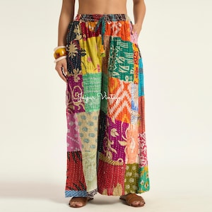 Puede incluir: Pantalones de pierna ancha con un diseño de patchwork colorido que presenta varios patrones florales, geométricos y abstractos en tonos amarillo, naranja, rosa, verde y azul. Los pantalones tienen una cintura elástica con cordón y bolsillos laterales.