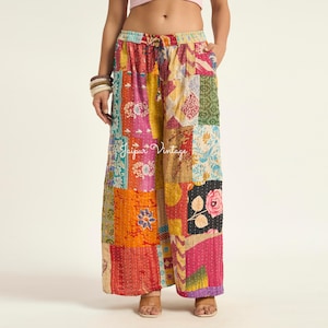 Puede incluir: Pantalones anchos con un diseño de patchwork que presenta varios cuadrados de tela coloridos en tonos rosa, naranja, amarillo, verde y azul. Los pantalones tienen una cintura elástica con cordón y costuras blancas visibles. El texto Jaipur Vintage es visible.