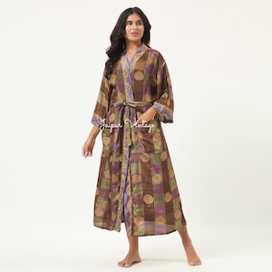 May include: A long-sleeved robe featuring a patchwork pattern of brown, purple, and green squares with circular gold-toned motifs. The garment includes a matching tie belt at the waist, two front pockets, and a purple trim along the front opening.