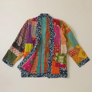 Puede incluir: Una chaqueta de manga larga confeccionada con un patchwork de paneles de tela multicolor que presentan diversos motivos florales, geométricos y de cachemira en tonos rosa, naranja, amarillo, verde y azul, con un borde estampado en azul oscuro.
