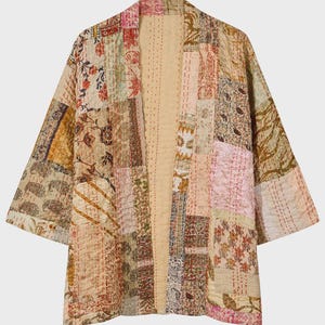 Könnte beinhalten: Eine Patchwork-Jacke mit einer Vielzahl von Blumen- und geometrischen Mustern in gedeckten Beige-, Rosa-, Braun- und Cremetönen. Das Kleidungsstück ist mit sichtbaren Steppnähten versehen und verfügt über ein offenes Vorderteil.