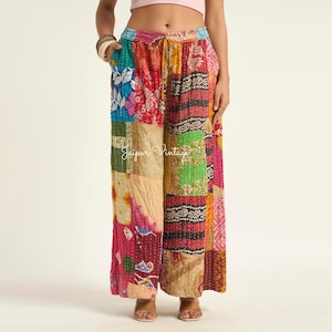 Könnte beinhalten: Weit geschnittene Hose mit Patchwork-Design und verschiedenen bunten Mustern, darunter florale, geometrische und abstrakte Drucke in Rosa-, Grün-, Gelb- und Blautönen. Die Hose hat einen elastischen Bund mit Kordelzug und sichtbaren Nähten.