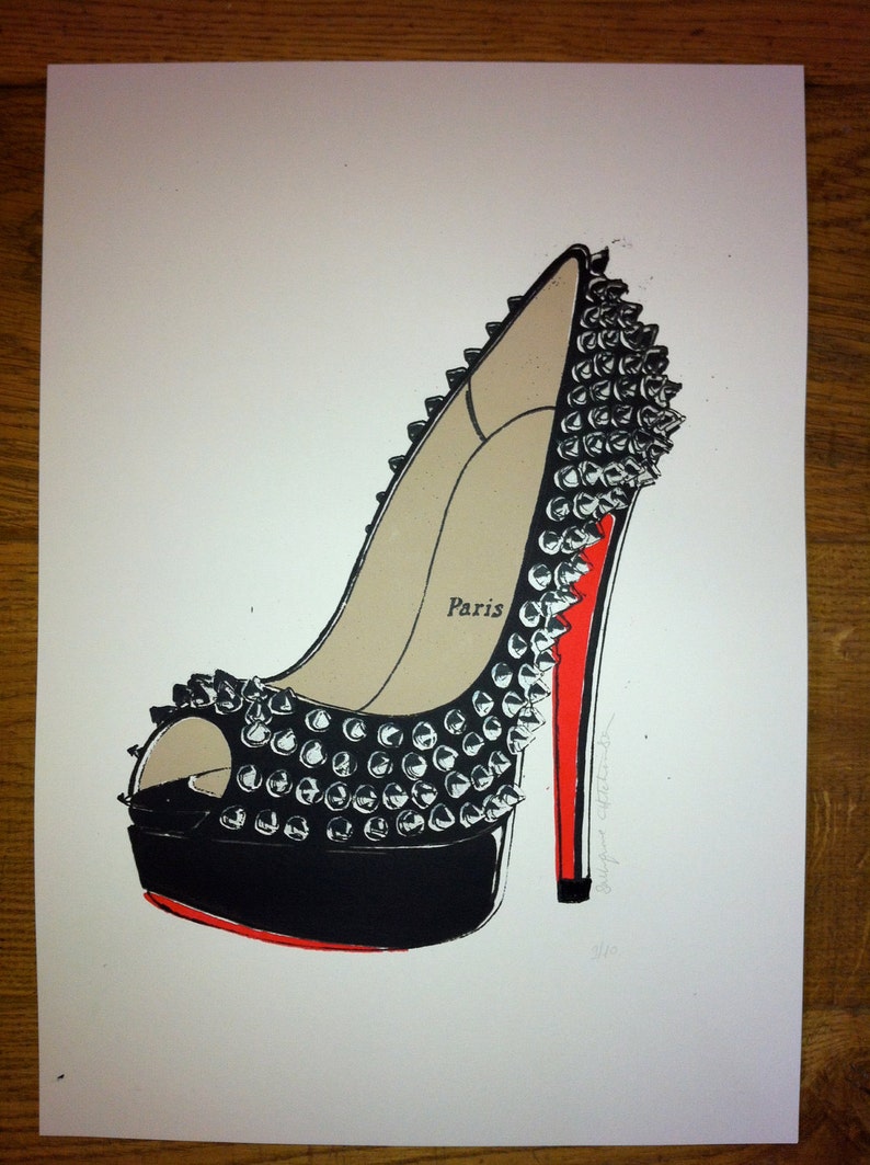 Puede incluir: Ilustraci&oacute;n de un zapato de tac&oacute;n alto con plataforma y tac&oacute;n negros, adornado con tachuelas plateadas. El zapato tiene un interior beige con la palabra "Paris" impresa y una suela roja.