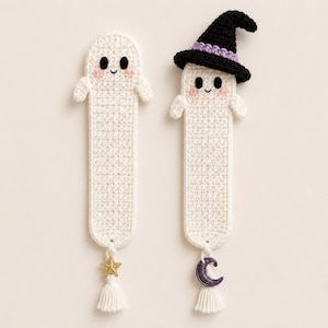 May include: Two off-white crocheted ghost bookmarks. One ghost has a simple rounded head, while the other wears a black witch hat with a purple band. Both have black eyes, pink cheeks, and a small tassel at the bottom with a gold star or purple moon charm.