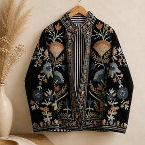 May include: A black jacket featuring intricate floral embroidery in shades of blue, orange, and green. The garment has a mandarin collar, long sleeves, and an open front design that reveals a black and white vertical striped lining on the interior.