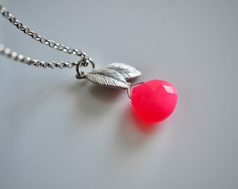 May include: A silver chain necklace with a pendant featuring two silver leaves and a bright pink gemstone.
