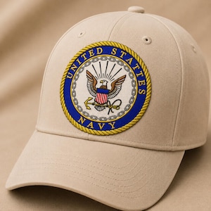 Könnte beinhalten: Eine beigefarbene Baseballkappe mit einem runden gestickten Aufnäher auf der Vorderseite. Der Aufnäher zeigt das Emblem der United States Navy mit einem Adler, Schild und Anker, umgeben von einem blauen Rand mit dem Text UNITED STATES NAVY.