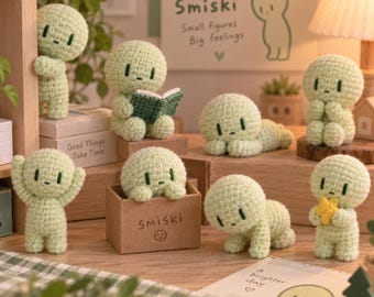 May include: A collection of eight small, light green crocheted figures with round heads and simple dark green embroidered facial features. The figures are posed in various positions, including sitting, lying down, and standing, with one holding a small yellow star.