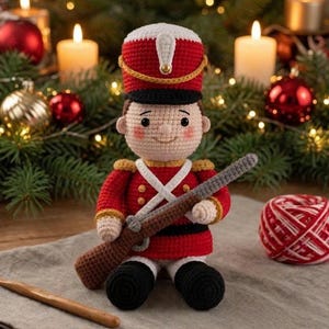 May include: A crocheted toy soldier doll wearing a red and white uniform with a tall hat, black boots, and gold accents. The doll has a light skin tone, rosy cheeks, and holds a brown crocheted musket across its chest. The figure is crafted with detailed yarn stitching and features a small gold button on the hat.