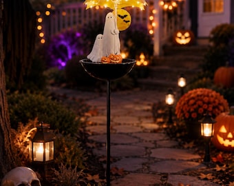 May include: A solar-powered garden stake featuring two white ghost figures standing under a yellow umbrella illuminated by small LED lights. The ghosts are positioned in a black bowl atop a thin black metal pole, with two small orange pumpkins.