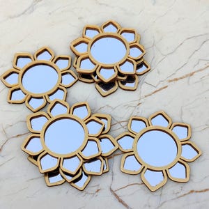 May include: A collection of small, circular mirrors with gold-colored frames shaped like flower petals. Each mirror features a central round glass pane surrounded by eight distinct, petal-like segments, creating a uniform floral silhouette across all pieces.
