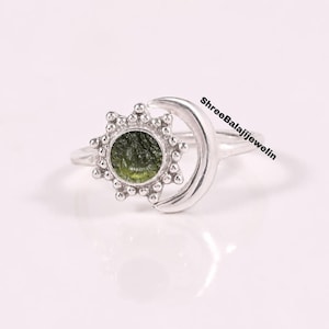 Könnte beinhalten: Ein Silberring mit einem kreisförmigen Sonnenmotiv, einem texturierten olivgrünen Stein in der Mitte und einer seitlich angebrachten Mondsichel. Der Ring ist aus glattem, poliertem Silber gefertigt. Der Text ShreeBalajiJewelin ist auf dem Ring zu sehen.